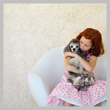 Girl (10-11) Sitting in a Chair and Holding a Poodle --- Image by © Royalty-Free/Corbis